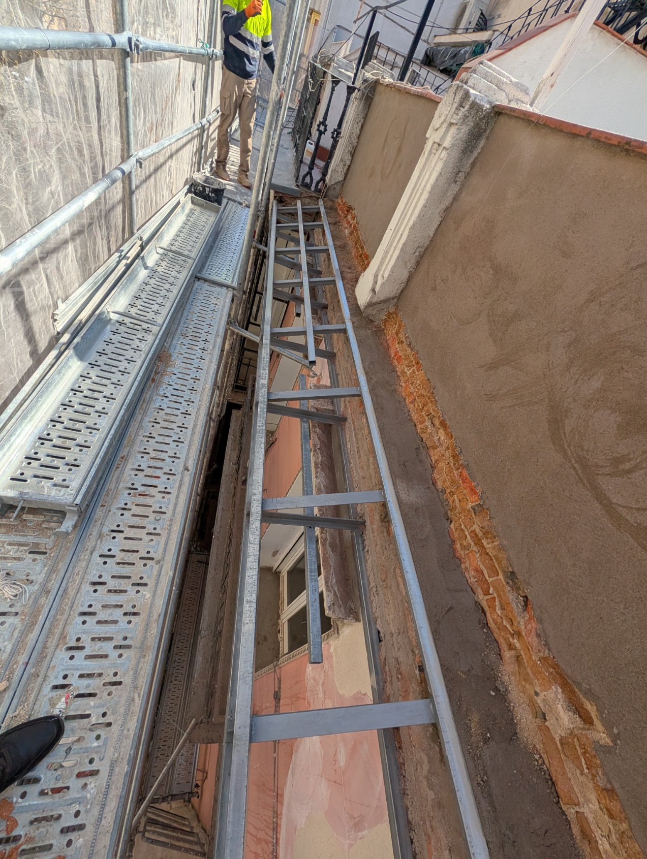 Vista general del refuerzo estructural con operario, andamio y protecciones en fachada de Chamberí