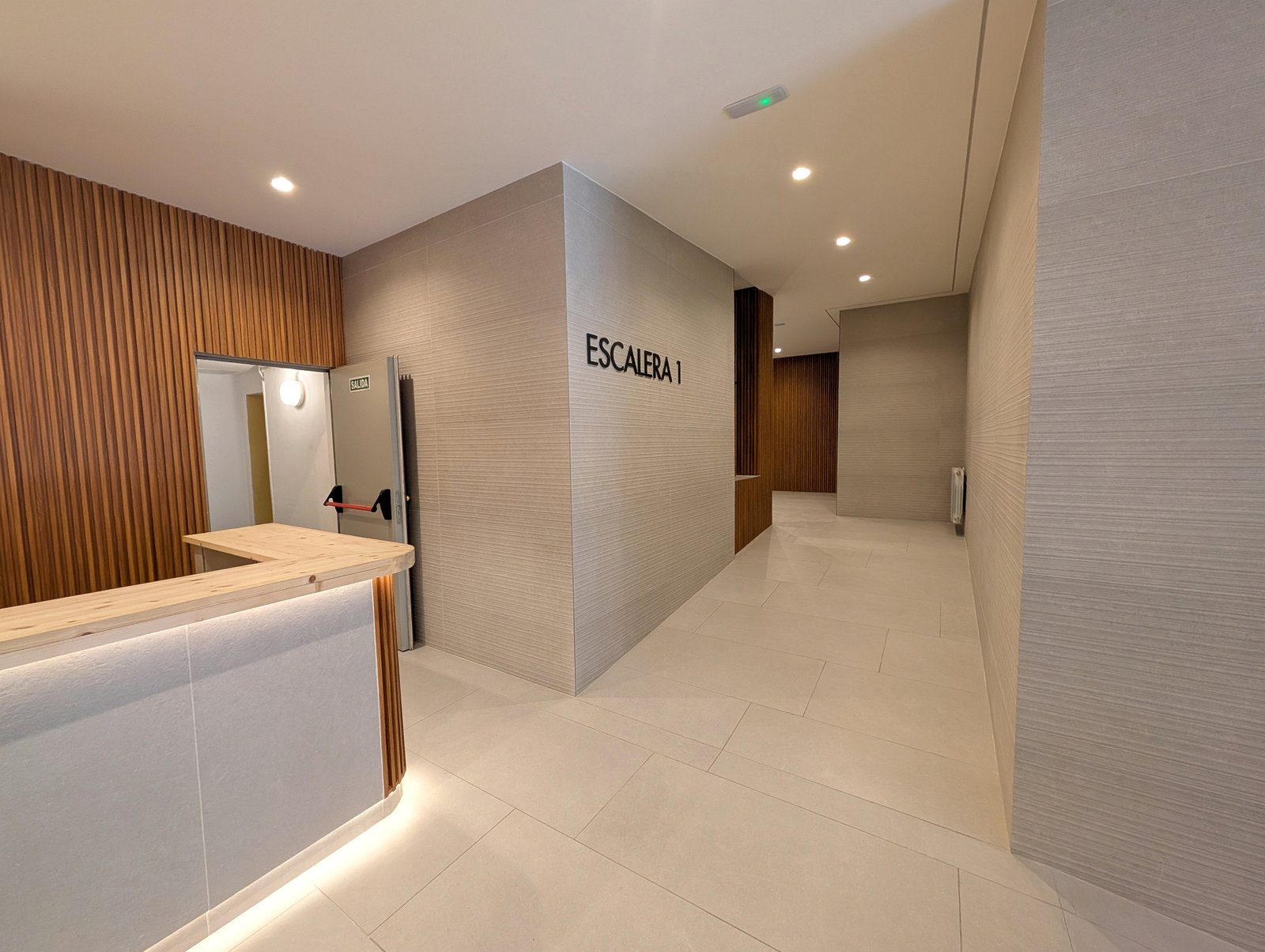 Zona de acceso a escaleras con acabados premium y señalética minimalista · Grupo Illescas
